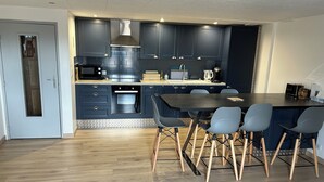 Una cocina moderna con armarios oscuros, una isla central con sillas y electrodomésticos integrados.