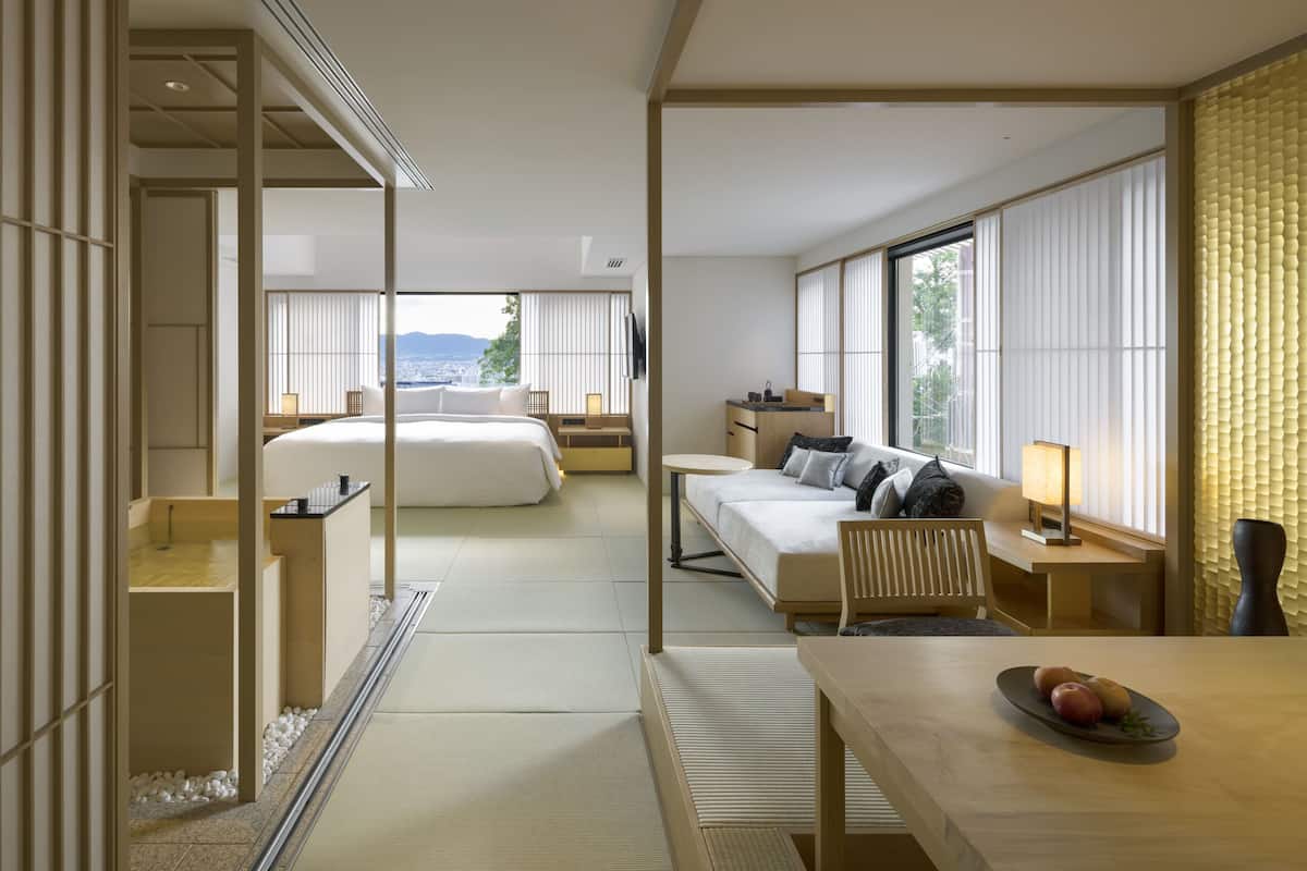 A hotel room with a large bed, a desk, and a view of the city.
