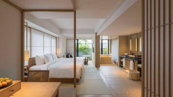 A modern hotel room with a large bed, a desk, a bathroom with a bathtub, and a view of greenery outside.