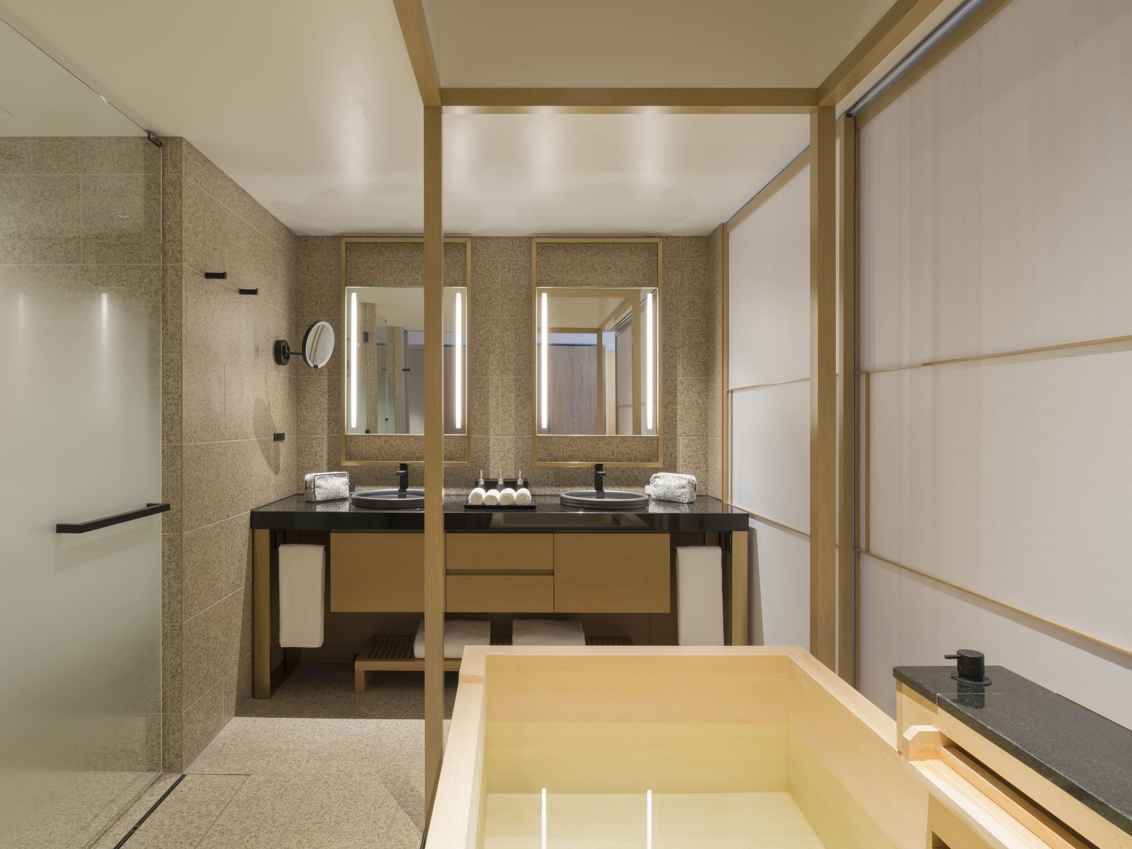 A modern bathroom with a double sink vanity, a large mirror, and a shower area.