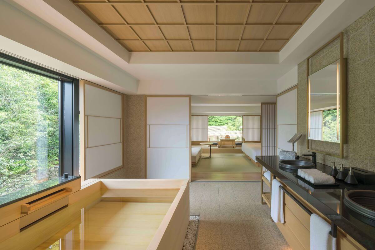 A modern interior with a kitchen area, a dining space, and a view of greenery outside.