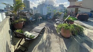 Une terrasse sur le toit agrémentée de plantes en pot, de chaises longues et d’une petite table.