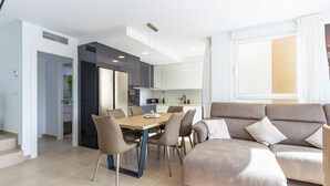 A modern living room with a sofa, a dining table with chairs, and a kitchen area with appliances. - Cozy home in Cartagena (Cartagena)