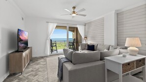 Ein modernes Wohnzimmer mit einer Couch, einem Fernseher und einem Deckenventilator.