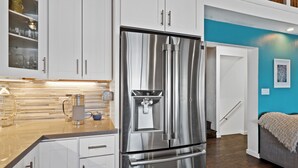 A modern kitchen with stainless steel appliances, white cabinetry, and a teal accent wall. - Lakefront, 1 King Bed, dock, mist view, electronic firepit (Lower Lake)