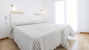 Ein Schlafzimmer mit einem Bett, zwei Nachttischen, einer Steckdose und einem Fenster.