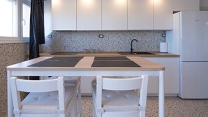 Una cocina moderna con armarios blancos, encimera de granito, grifo negro y refrigerador blanco.