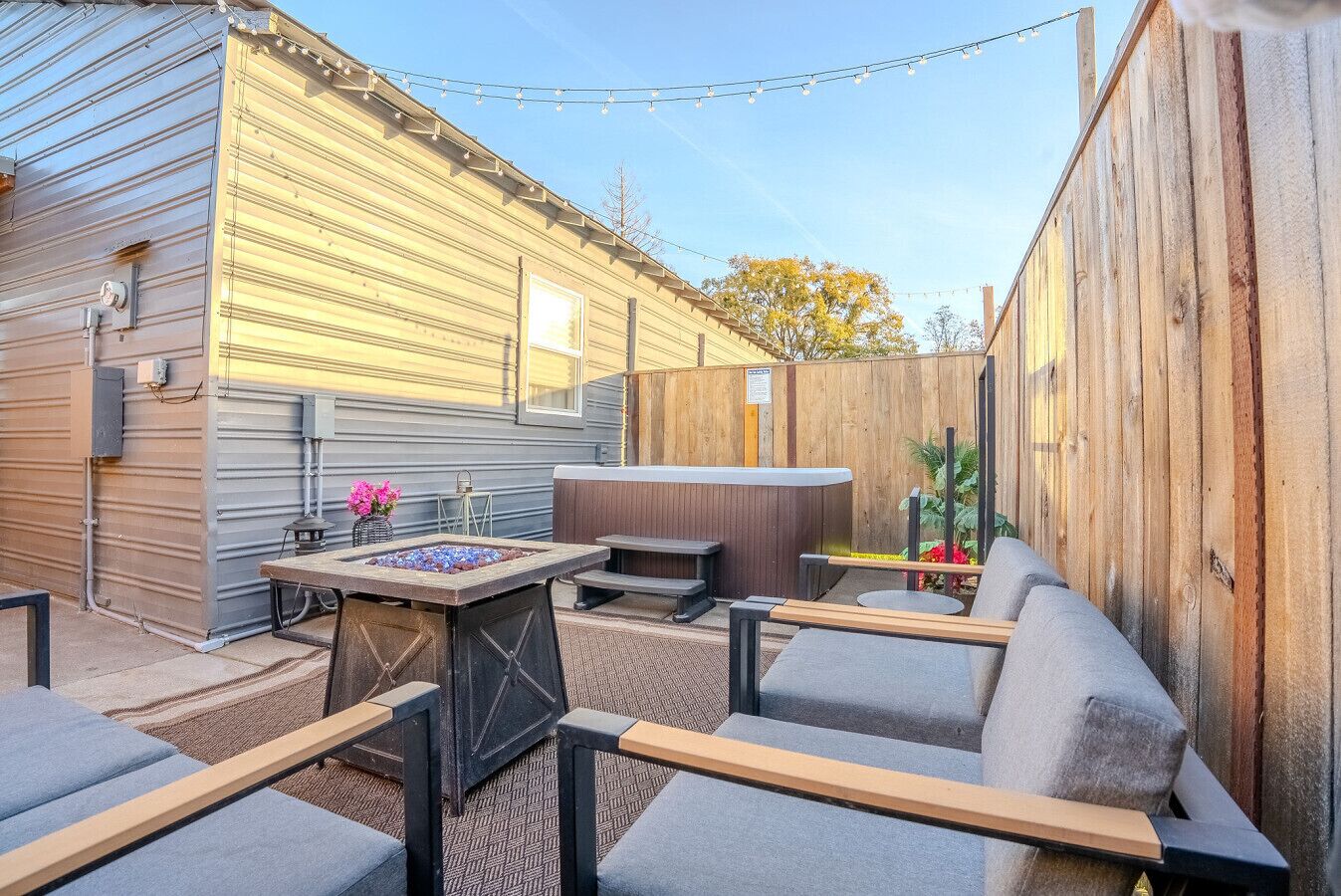 A backyard with a hot tub, outdoor seating, and a fire pit.