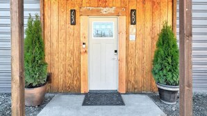 A wooden entrance with a white door, two potted plants, and a metal gate. - Spacious Cottage -Hot Tub, Patio, Fire Table, WIFI (Central Point)
