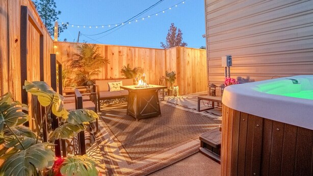 A backyard with a hot tub, outdoor seating, and string lights. - Spacious Cottage -Hot Tub, Patio, Fire Table, WIFI (Central Point)