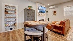 A living room with a round table, a sofa, a TV, and a bookshelf. - Spacious Cottage -Hot Tub, Patio, Fire Table, WIFI (Central Point)