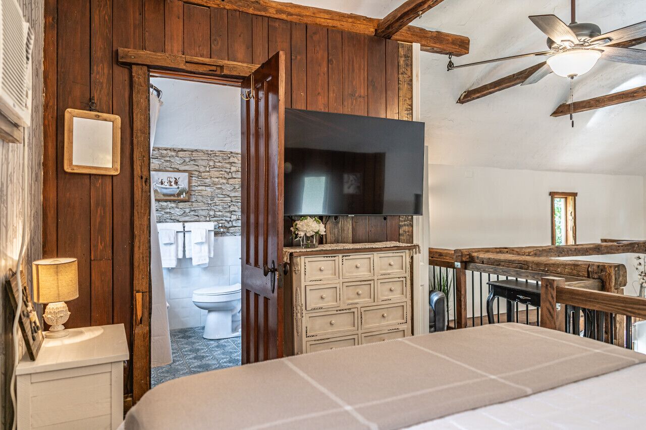 Une chambre à coucher avec un plafond en bois, un lit, une commode et un téléviseur.