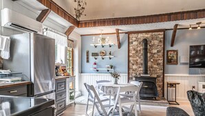 A modern kitchen with a built-in stove, white cabinetry, and a dining area with a round table and chairs.