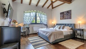 Ein Schlafzimmer mit einem großen Bett, einem Schreibtisch, einem Stuhl und einem Fernseher.