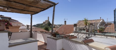 A rooftop terrace with a pergola, seating area, and a view of the cityscape including a church.