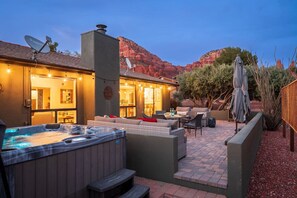 A cozy outdoor patio with a hot tub, seating area, and a view of red rock formations. - High-end 3BR Home w/ Spa, Firepit & Red Rock Views (Sedona)