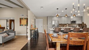Una cucina moderna con mobili grigi, un frigorifero in acciaio inossidabile e un'area pranzo con sedie e tavolo in legno.