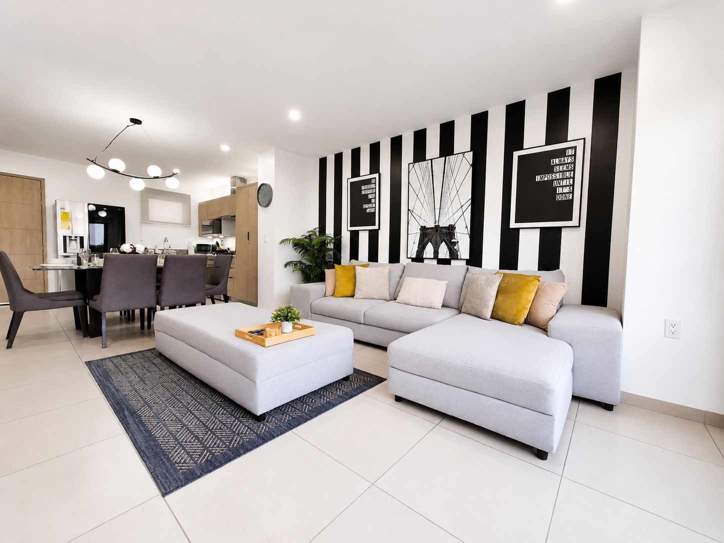 A modern living room with a sofa, ottoman, and dining area with chairs and a table.