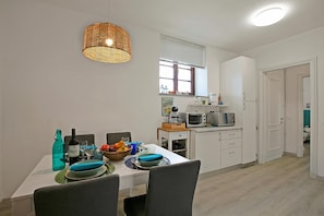 A modern kitchen with white cabinets, a dining table set with plates and glasses, and a hanging light fixture. - Elizabeth House-100m lake & priv.parking, Toscolano Maderno, Italy (Toscolano Maderno)