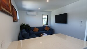 A modern living room with a marble countertop, a blue sofa, and a flat-screen TV mounted on the wall. - Broadbeach Tropical Gem with Lux features (Broadbeach Waters)