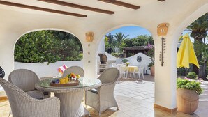 An outdoor patio with wicker furniture, a glass table, and a yellow umbrella. - Navarra by Interhome (Moraira)