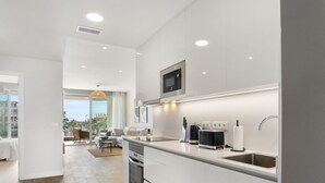 A modern kitchen with white cabinetry, a built-in oven, and a stainless steel sink.
