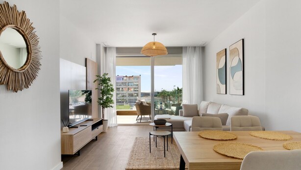 A modern living room with a TV, sofa, dining table, and a large window offering a view of the city.