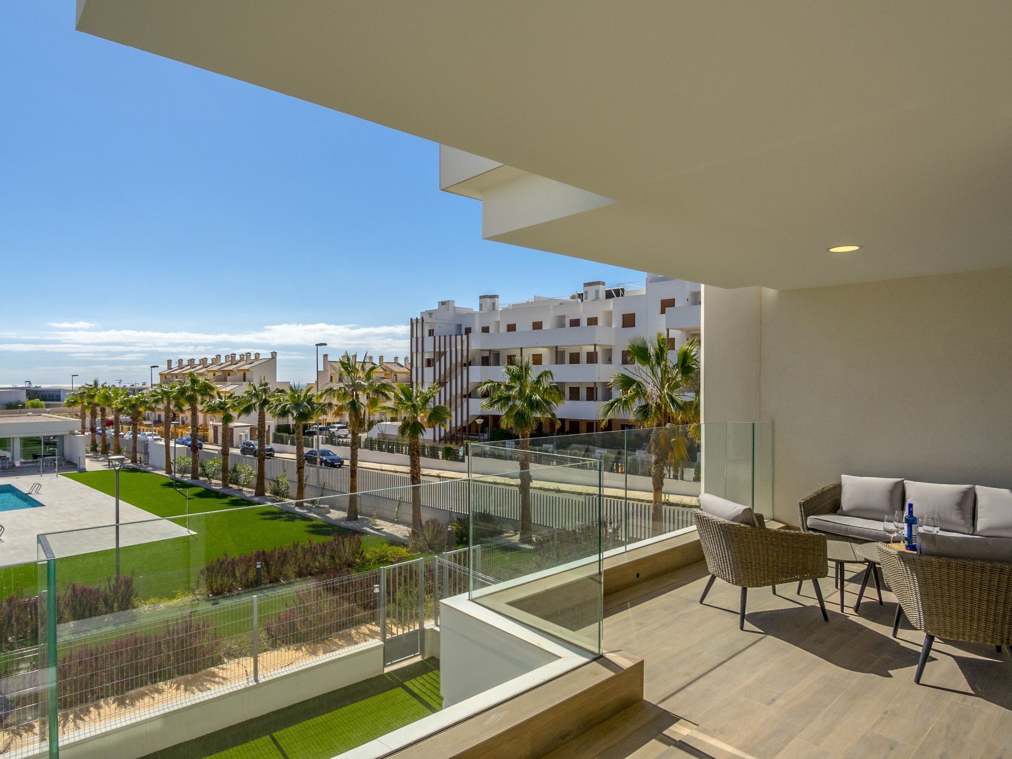 Un balcón con vista a una piscina, palmeras y edificios.