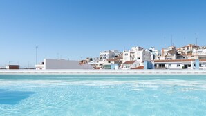 A coastal hotel with a pool, white buildings, and a clear blue sky. - Ideal long stay: central, parking and pool (Sant Pol de Mar)