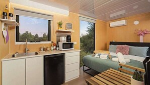 A compact room with a kitchenette, a bed with a view, and a small seating area.