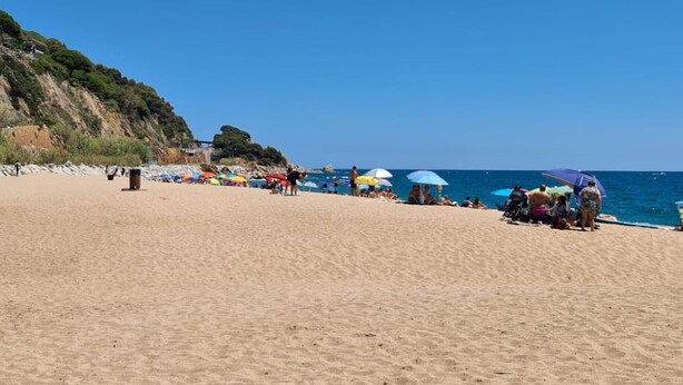 Une plage où des gens se prélassent au soleil et se promènent le long du rivage.