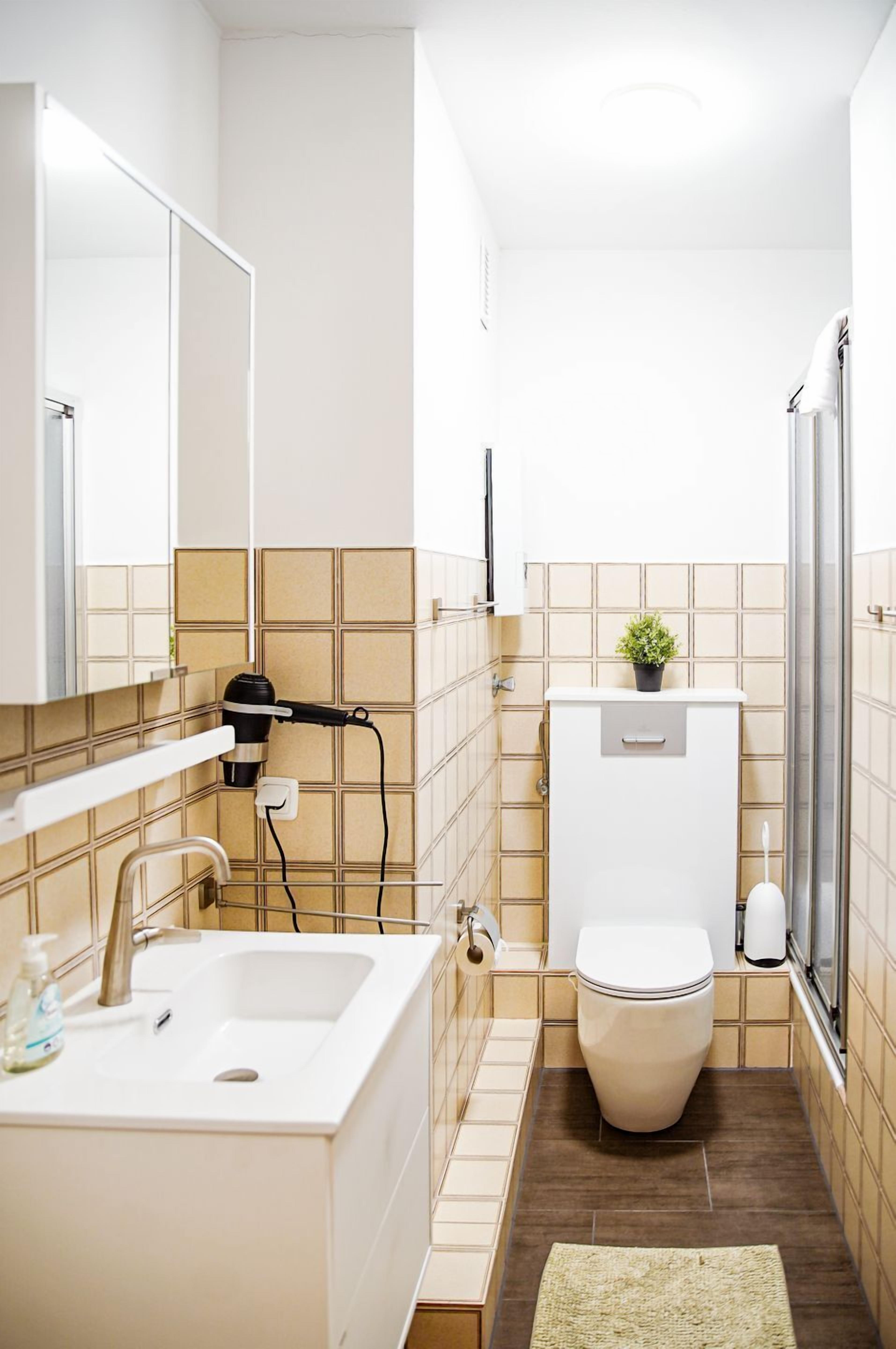 Une petite salle de bain avec un lavabo blanc, des toilettes et un espace douche.
