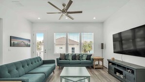 A living room with a green sofa, a coffee table, a TV, and a ceiling fan. - Twente Toes (Navarre)