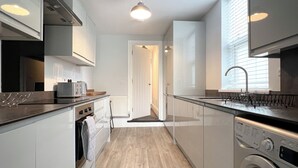 Une cuisine moderne équipée d’un four, d’un micro-ondes et d’un lave-linge intégrés.