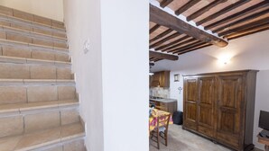 Una escalera conduce a una cocina con armarios de madera y un comedor.