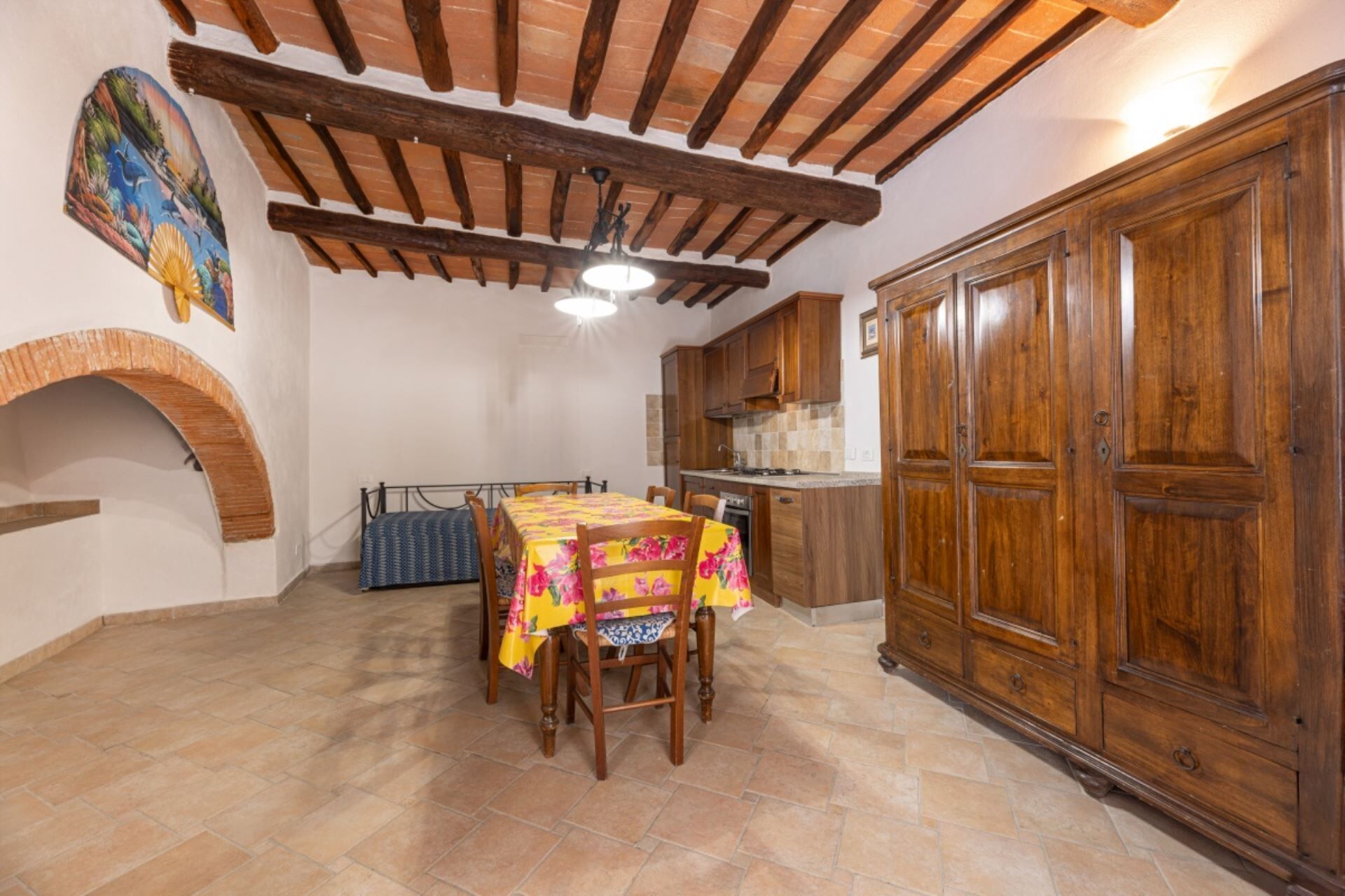 Un comedor con una mesa dispuesta para cuatro personas, armarios de madera y piso de baldosas.