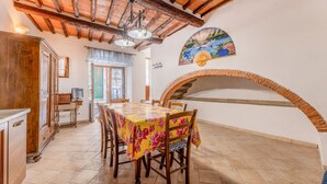 Un comedor con una mesa dispuesta para seis personas, un aparador de madera y un abanico decorativo en la pared.
