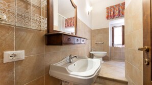 Un baño con lavabo, espejo e inodoro.