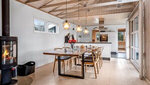 Een moderne keuken met houten balken, een centraal eiland, hangende lampen en een zichtbaar fornuis.