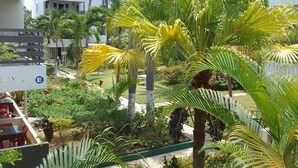 A lush outdoor garden with palm trees and various plants, surrounded by buildings. - Studio Apt on 7 Mile Beach at Negril Beach Club (Negril)