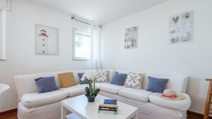 Uma sala de estar moderna com um sofá branco, uma mesa de centro e uma pequena planta em vaso.