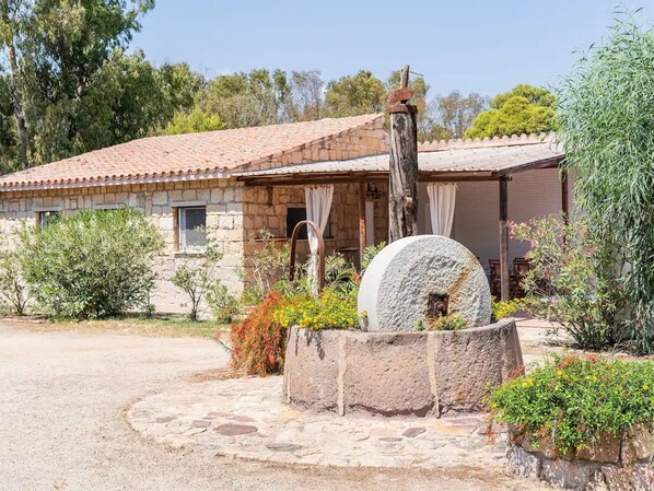A stone house with a tiled roof, a stone well, and surrounding vegetation. - Villa Ilse by Interhome (Pula)