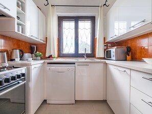 A modern kitchen with white cabinets, a dishwasher, a stove, and a microwave. - Villa Grete by Interhome (Pula)