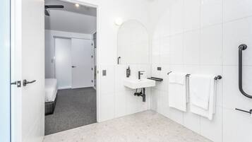 A modern bathroom with a white sink, mirror, and towel rack.