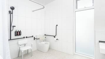 Een moderne badkamer met witte tegels, een douche met een gebogen douchekop, een toilet met een handgreep en een witte stoel.