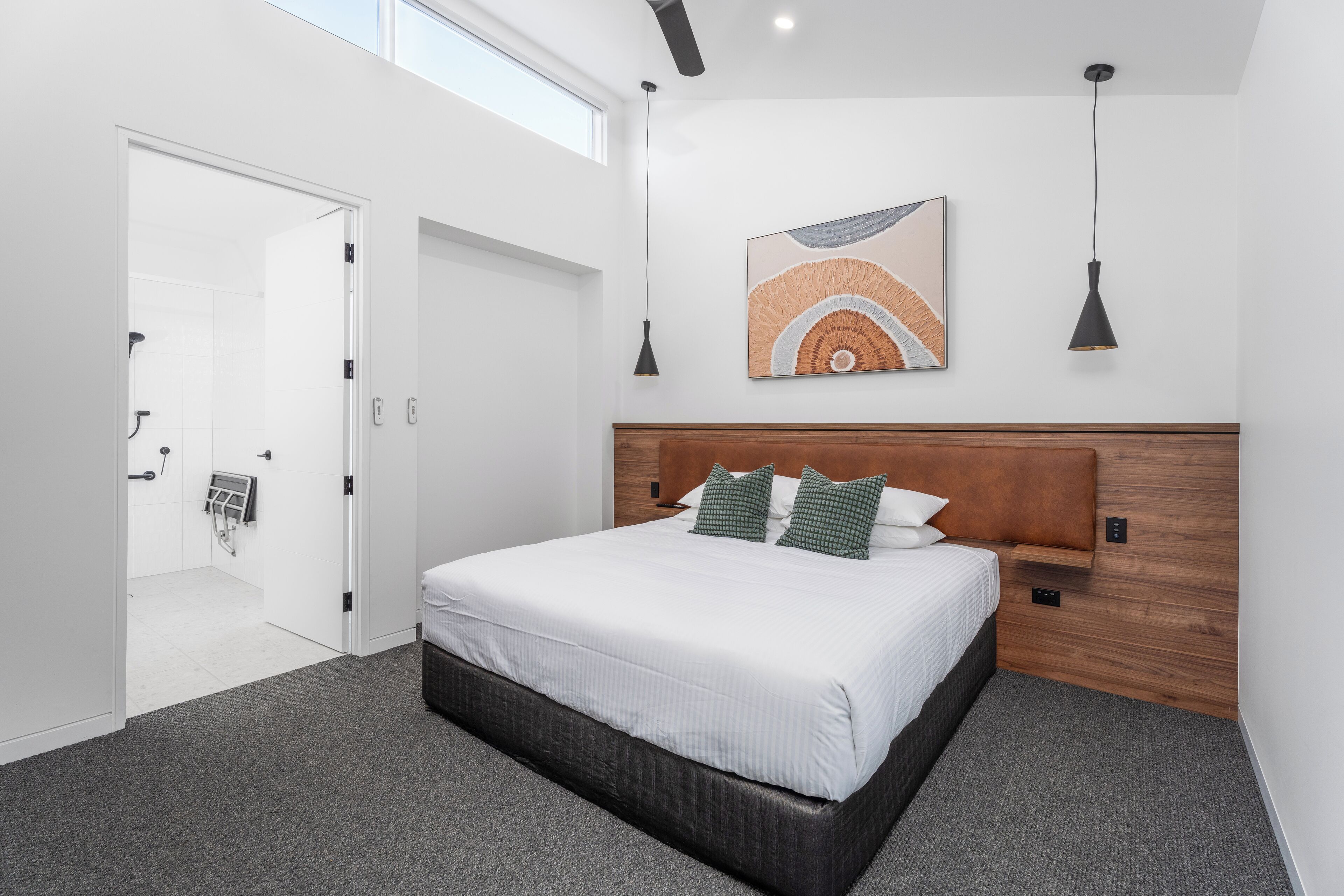 Ein modernes Schlafzimmer mit einem großen Bett, einem Holzkopfende, einem Deckenventilator und einem Wandbild.