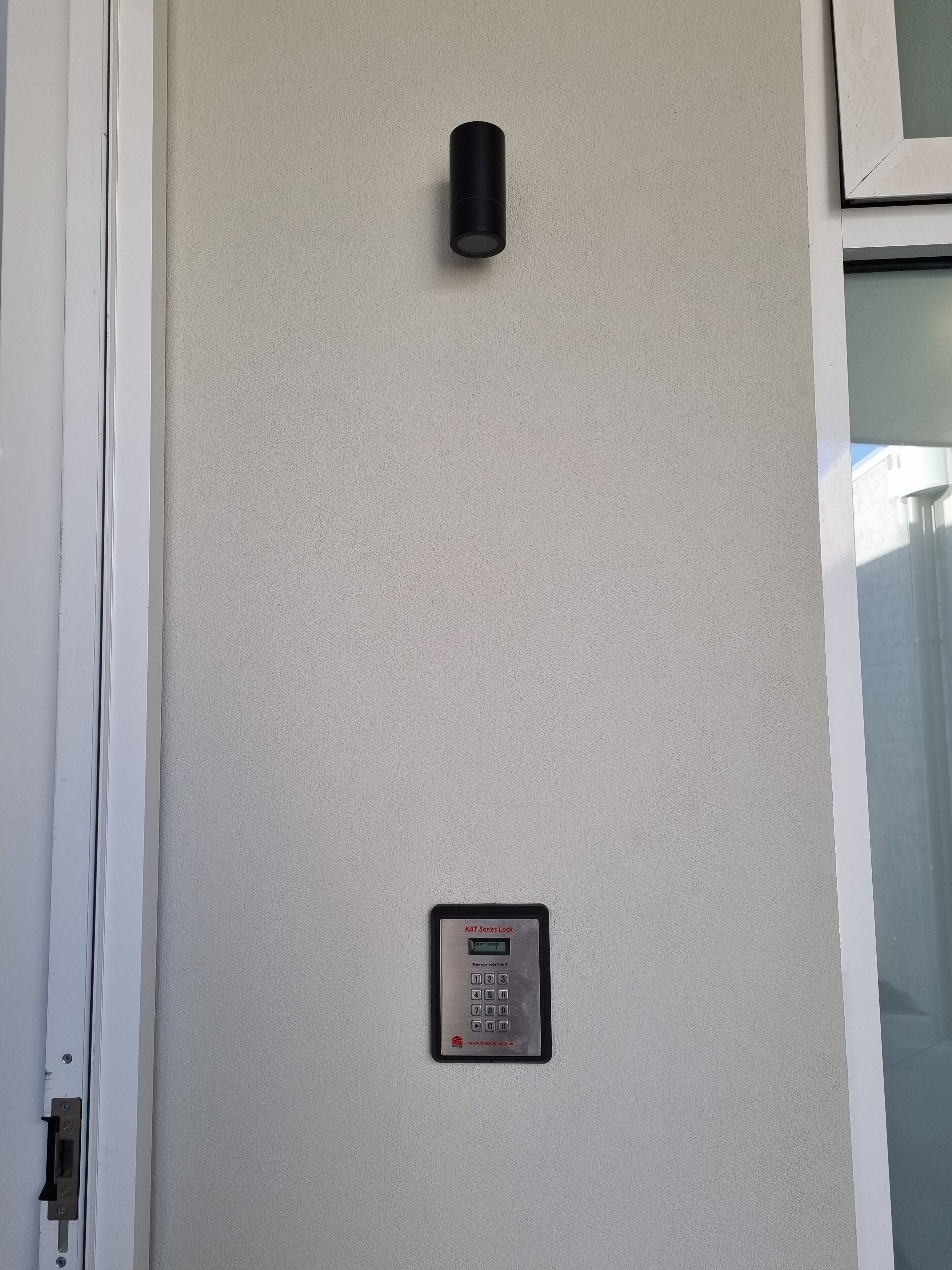 Ein an der Wand montiertes Gegensprechanlage mit Tastatur und einem kleinen Schild darüber.