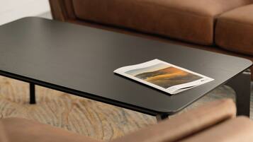 A brown leather sofa and a black coffee table with a magazine.