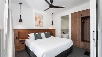 Un dormitorio moderno con una cama grande, cabecera de madera, ventilador de techo, lámparas colgantes y un armario.