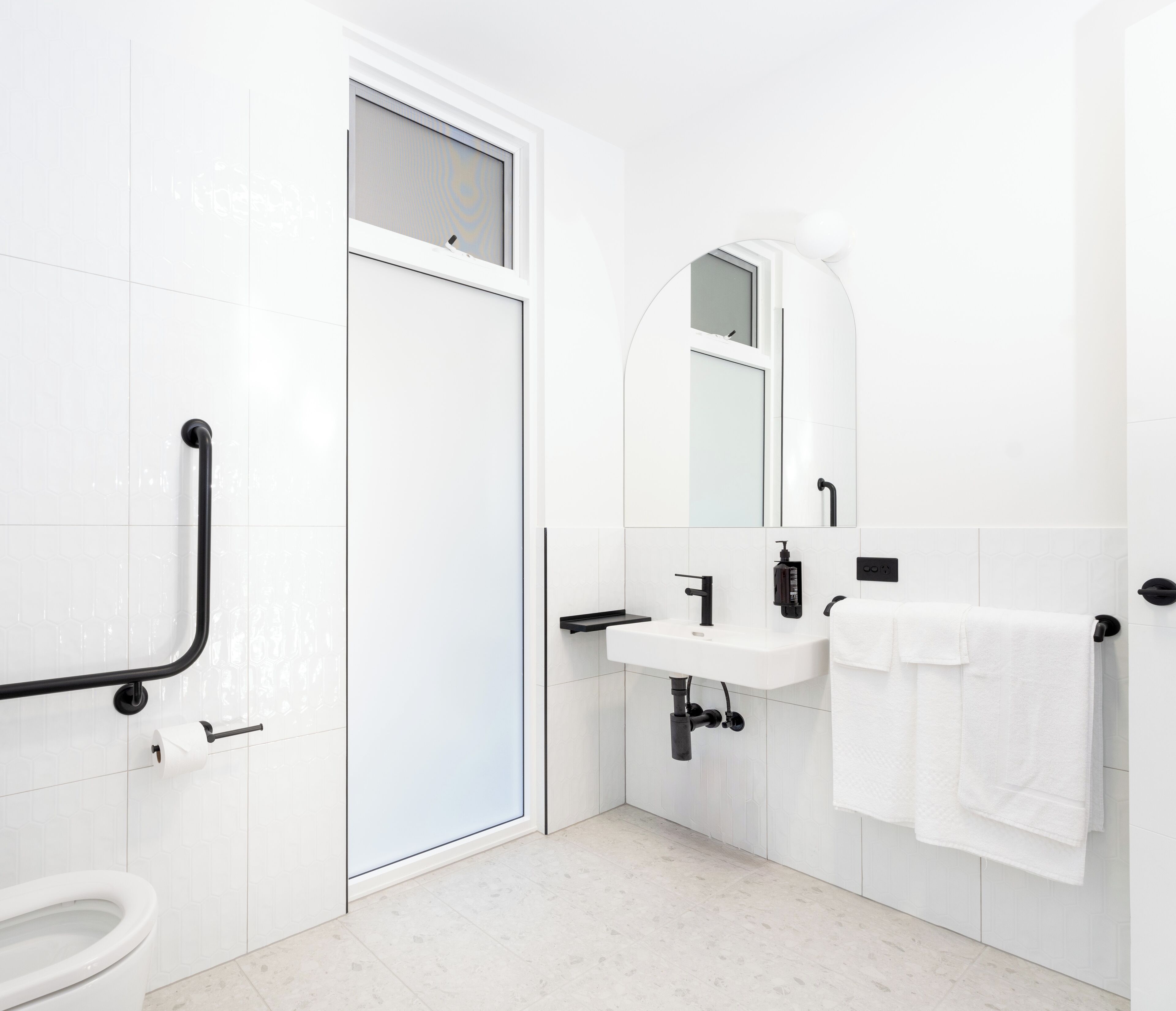 Un bagno moderno con lavandino, specchio e water bianchi.